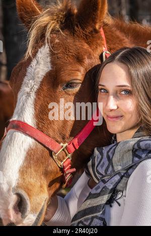 Hübsches braunes Cowgirl, das einen Tag mit ihrem Pferd auf der Farm genießt Stockfoto