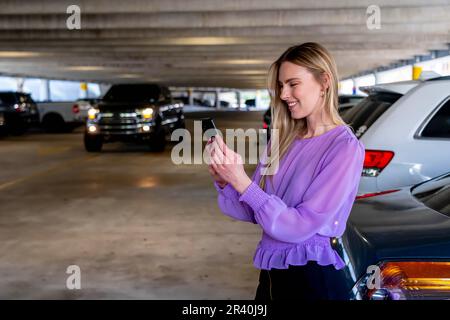 Eine hübsche blonde Assistentin geht nach Einem langen Tag auf Einem überdachten Parkplatz zu ihrem Auto Stockfoto