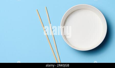 Öffnen Sie die leere Nudelschüssel mit einem Paar Holzstäbchen auf blauem Hintergrund, Draufsicht Stockfoto