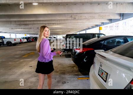 Eine hübsche blonde Assistentin geht nach Einem langen Tag auf Einem überdachten Parkplatz zu ihrem Auto Stockfoto