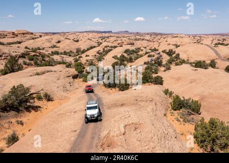 Jeeps und Off Highway-Fahrzeuge oder OHVs fahren über die Sandsteinkuppeln des Fins & Things Trail in der Nähe von Moab, Utah. Stockfoto