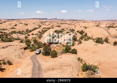 Jeeps und Off Highway-Fahrzeuge oder OHVs fahren über die Sandsteinkuppeln des Fins & Things Trail in der Nähe von Moab, Utah. Stockfoto