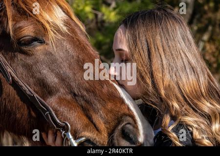 Ein wunderschönes braunes Cowgirl posiert mit ihrem Pferd, bevor es auf dem Land reitet Stockfoto