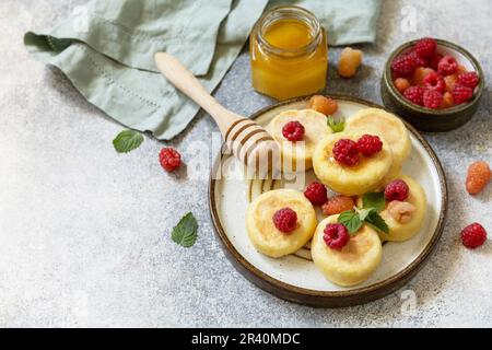 Hausgemachter Hüttenkäse Pfannkuchen glutenfrei (Syrniki, Quark-Fritters) mit Beeren auf einem Steinhintergrund. Ricotta-Pfannkuchen, morgen Stockfoto