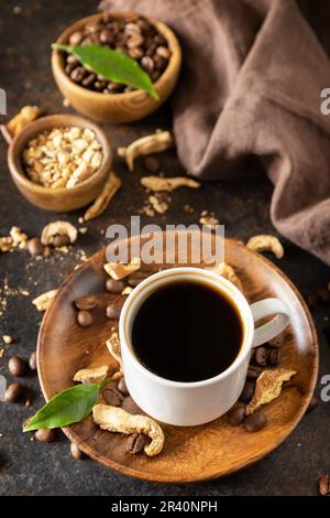 Pilzkaffee in einer Tasse und Kaffeebohnen, trendiges Getränk auf Steinhintergrund. Gesundes organisches energiegeladenes Adaptogen. Stockfoto