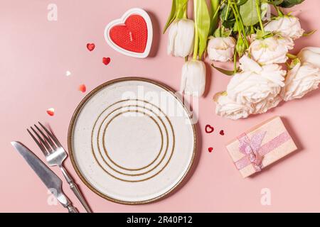 Valentinstag, Frauentag, Muttertag Grußkarte. Menü zum Valentinstag und wunderschöne Frühlingsblumen auf hellrosa Hintergrund Stockfoto