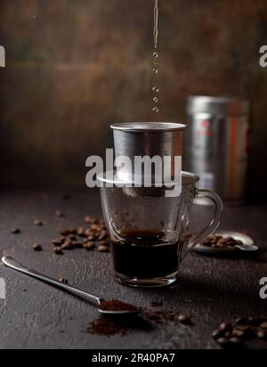 Vorbereitung der vietnamesischen Kaffee mit Aluminium cofe Filer auf dunklem Hintergrund Stockfoto