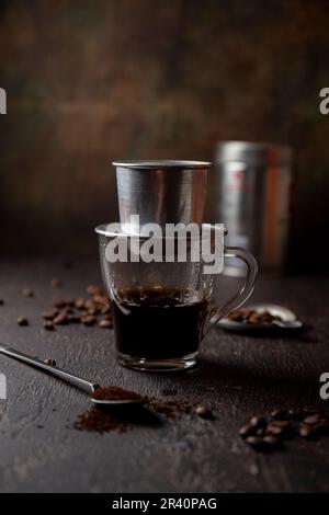 Vorbereitung der vietnamesischen Kaffee mit Aluminium cofe Filer auf dunklem Hintergrund Stockfoto