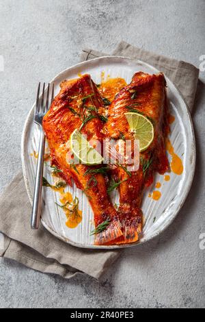 Gebackene rote Meer Bass auf Kraftpapier weiße Platte, konkreten Hintergrund. Stockfoto