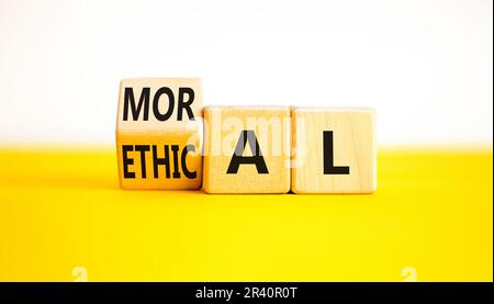 Ethisches oder moralisches Symbol. Ein Geschäftsmann verwandelt Holzwürfel und ändert das Wort ethisch in moralisch auf einem wunderschönen gelben, weißen Hintergrund. Geschäft A Stockfoto