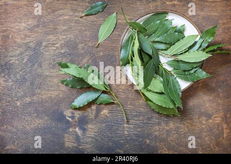 Kräuter und Gewürze: lorbeerblätter. Frische Lorbeerblätter auf rustikalem Holzhintergrund. Blick von oben. Stockfoto