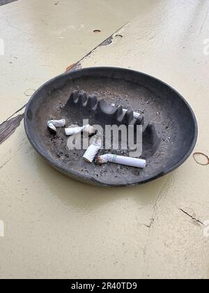 Rauchte Zigarette auf schwarzem Aschenbecher auf Picknicktisch. Stockfoto