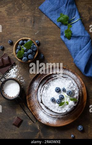 Pfannkuchen-Tag, Sommerdessert. Köstliche hausgemachte amerikanische Bananen Schokoladen-Pfannkuchen mit Blaubeeren auf einem rustikalen Tisch. Ansicht von Stockfoto