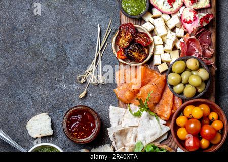 Antipasto. Wein-Set-Vorspeise. Schinken serrano, geräucherter Lachs, getrockneter und frischer Tomatenkäse, Wein an Bord. Draufsicht, grau Stockfoto