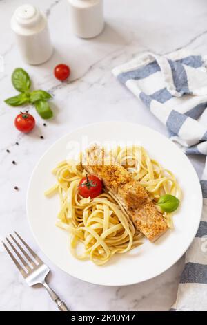 Glutenfreie Spaghetti-Pasta mit gegrilltem Lachs in Frischkäse auf Marmorhintergrund. Stockfoto