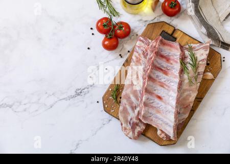 Rohes Kalbsbriketts Fleisch mit Gemüse und Gewürzen auf kurzen Rippen zum Kochen auf Marmorplatte. Draufsicht, flach liegend. Stockfoto