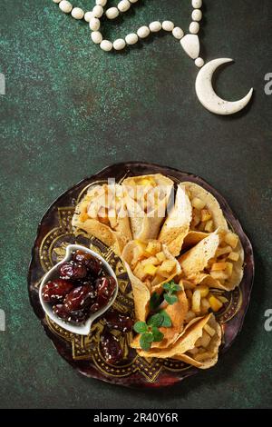 Ramadan Karäem festlich, Fasten, Halal-Essen. Ramadan-Menü, arabischer Pfannkuchen-Katayef (katajew, Katajef) mit Apfelfüllung und cin Stockfoto