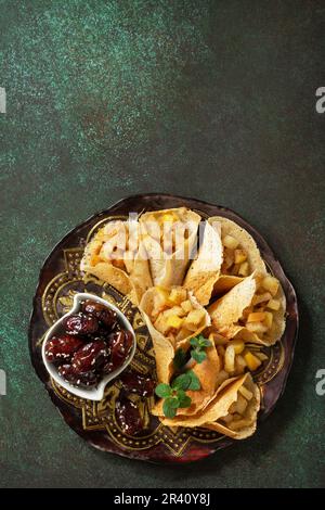 Ramadan Karäem festlich, Fasten, Halal-Essen. Ramadan-Menü, arabischer Pfannkuchen-Katayef (katajew, Katajef) mit Apfelfüllung und cin Stockfoto