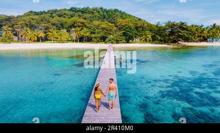 Ein Paar Männer und Frauen auf einem Holzboardspaziergang auf einer tropischen Insel in Thailand, Koh Kham bei Koh Mak Stockfoto