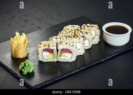 Sushi-Brötchen mit Thunfisch und Sesam auf dunklem Hintergrund. Sushi-Menü. Japanisches Essen. Stockfoto