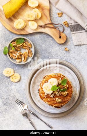 Zum Feiern des Pfannkuchen-Tages, amerikanisches hausgemachtes Frühstück. Glutenfreie Bananen-Pfannkuchen mit Nüssen und Karamell auf einer Tischplatte aus Stein. Anzeigen Stockfoto