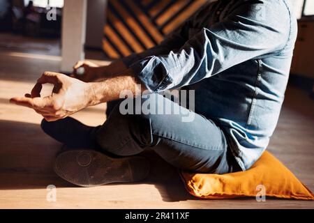 Ein hübscher lateinamerikanischer Mann mit Jeans, lässiges Hemd, der auf dem Floo sitzt Stockfoto