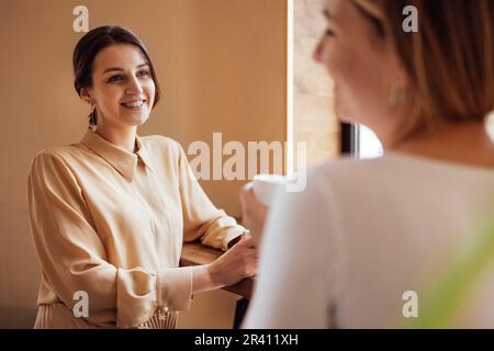 Glückliche junge Freundinnen, die eine Kaffeepause machen Stockfoto