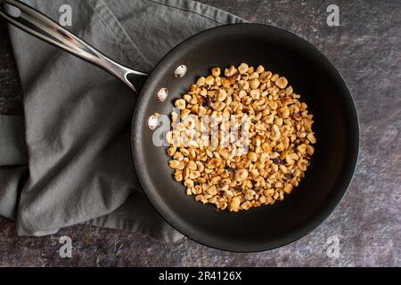 Geröstete Haselnüsse in einem Messbecher aus Edelstahl: Blick von oben auf gehackte Kopfnüsse nach dem Toasten in einer kleinen Fritteuse Stockfoto