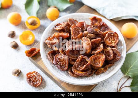 Getrocknete Früchte. Getrocknete Aprikosen und rohe Aprikosen auf grauem Steingrund. Stockfoto