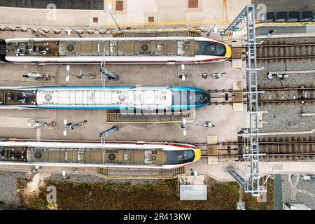 Luftaufnahme direkt über Hochgeschwindigkeitszügen in einem Wartungshof mit freiliegenden Elektrodrähten Stockfoto