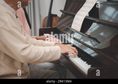 Glückliche Tochter und älterer Vater, die zusammen im Wohnzimmer Musik auf dem Klavier spielen Stockfoto