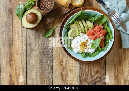 Köstliches Frühstück oder Lunch Schale mit salzem Lachsfisch, Avocado, gekochtem Ei und Spinat auf einem rustikalen Tisch. Ketogen, Keto oder Stockfoto