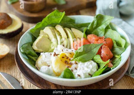 Köstliches Frühstück oder Lunch Schale mit salzem Lachsfisch, Avocado, gekochtem Ei und Spinat auf einem rustikalen Tisch. Ketogen, Keto oder Stockfoto