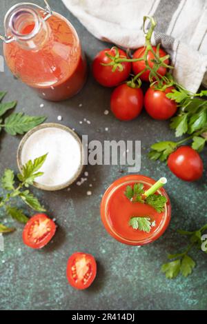 Herbst Vitamin trinken Saft Tomate. Tomatensaft im Glas und frische Tomaten auf einer steinernen Tischplatte. Blick von oben. Stockfoto