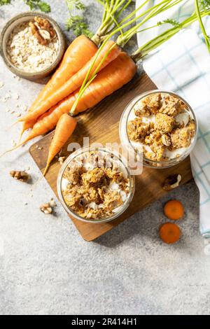 Gesundes Dessert. Veganes glutenfreies Gebäck. Karottenkuchen mit Walnüssen und Zimt in einem Glas auf hellem Hintergrund. Blick von ABO Stockfoto