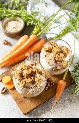 Veganes glutenfreies Backen. Karottenkuchen mit Walnüssen und Zimt in einem Glas auf hellem Hintergrund. Gesundes Dessert. Stockfoto