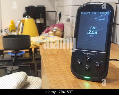 London, Großbritannien. 22. Mai 2023. Ein intelligenter Zähler in einer Küche sitzt auf einem Brotbehälter und erfasst die täglichen Gas- und Stromkosten, mit einem Kochfeld und einem gelben Wasserkocher auf der Küchentheke im Hintergrund. Die Energieregulierungsbehörde Ofgem hat soeben die Obergrenze für die Energiepreise gesenkt, wodurch ein durchschnittlicher Kunde £426 US-Dollar pro Jahr einsparen wird. Kredit: Anna Watson/Alamy Live News Stockfoto