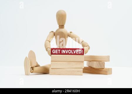 Geschäftskonzept. Auf einer weißen Oberfläche sitzt ein Mann aus Holz in seinen Händen. Ein Block mit der Inschrift Stockfoto