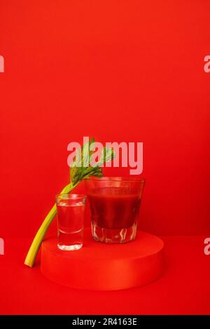 Ein Glas roter Cocktail mit Grün auf dem Podium. Stilvolles alkoholisches Tomatengetränk Bloody Mary Stockfoto