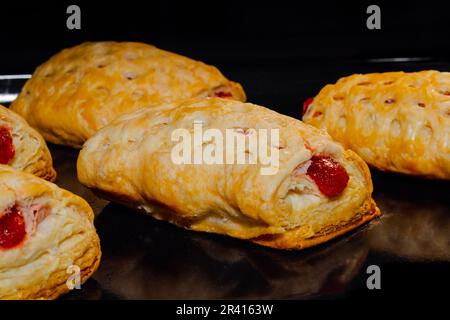Gebackene hausgemachte Brötchen mit roter Erdbeermarmelade im Elektroofen Stockfoto