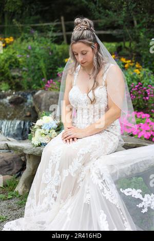 Die feierliche Hochzeitsbraut trägt weißes Kleid, sieht nach unten, meditiert und betet bei Wedding Stockfoto