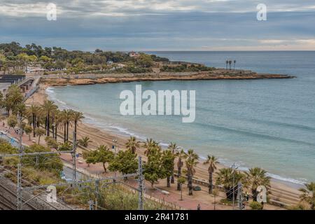 Platja del Miracle-Playa El Milagro die Promenade, die Straße und die Bahngleise mit dem Hafen der Stadt Tarragona in der Gemeinde Katalonien. Stockfoto