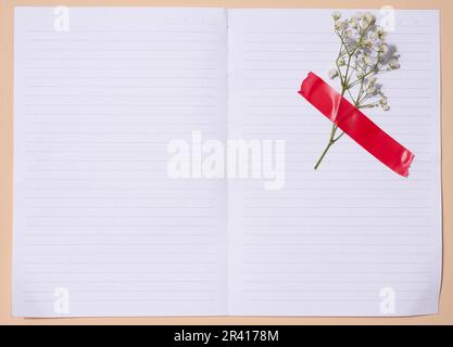 Leeres weißes Blatt Papier und Zigeunerblüten auf beigem Hintergrund, Platz für eine Inschrift Stockfoto