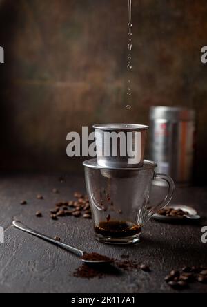 Vorbereitung der vietnamesischen Kaffee mit Aluminium cofe Filer auf dunklem Hintergrund Stockfoto