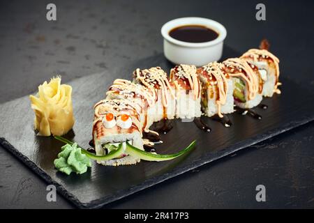 Brötchen aus frischem rohem Lachs, geräuchertem Aal, Frischkäse und Avocado im Inneren. Garniert mit geräuchertem Aal Unagi Stockfoto