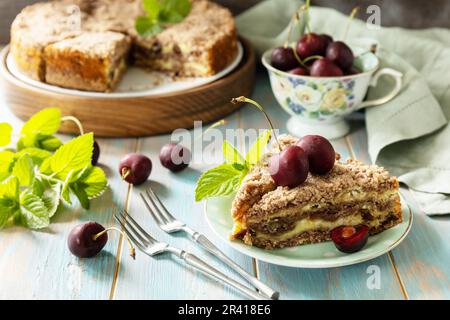 Hausgemachtes Sommergebäck glutenfrei. Schokoladen- und Quark-Kuchen mit Kirschen auf einem rustikalen Tisch. Stockfoto