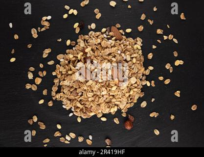 Gesundes Müsli mit Nüssen auf schwarzem Schieferhintergrund, Draufsicht Stockfoto