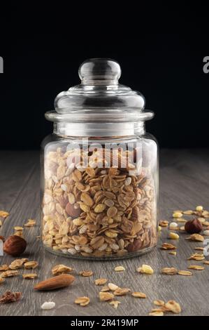 Hausgemachtes Müsli im Glas auf dem Küchentisch, gesundes Frühstück mit Haferbrei Müsli, Nüssen, Samen und getrockneten Früchten. Stockfoto