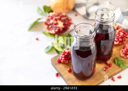 Granatapfelsaft in Glasflaschen und frische Granatapfelfrüchte. Gesunde Getränke Diät Immunität Vitamine oder vegetarisches Lebensmittelkonzept Stockfoto