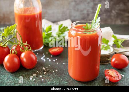 Herbst Vitamin trinken Saft Tomate. Tomatensaft im Glas und frische Tomaten auf einer steinernen Tischplatte. Stockfoto